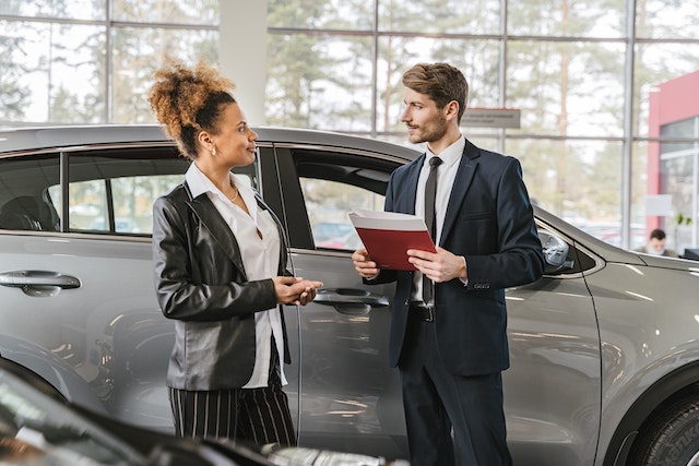 A Salesperson at Stokes Trainor, a Chevy Dealer in Newberry, SC. He is in the process of selling a gray SUV to a customer.