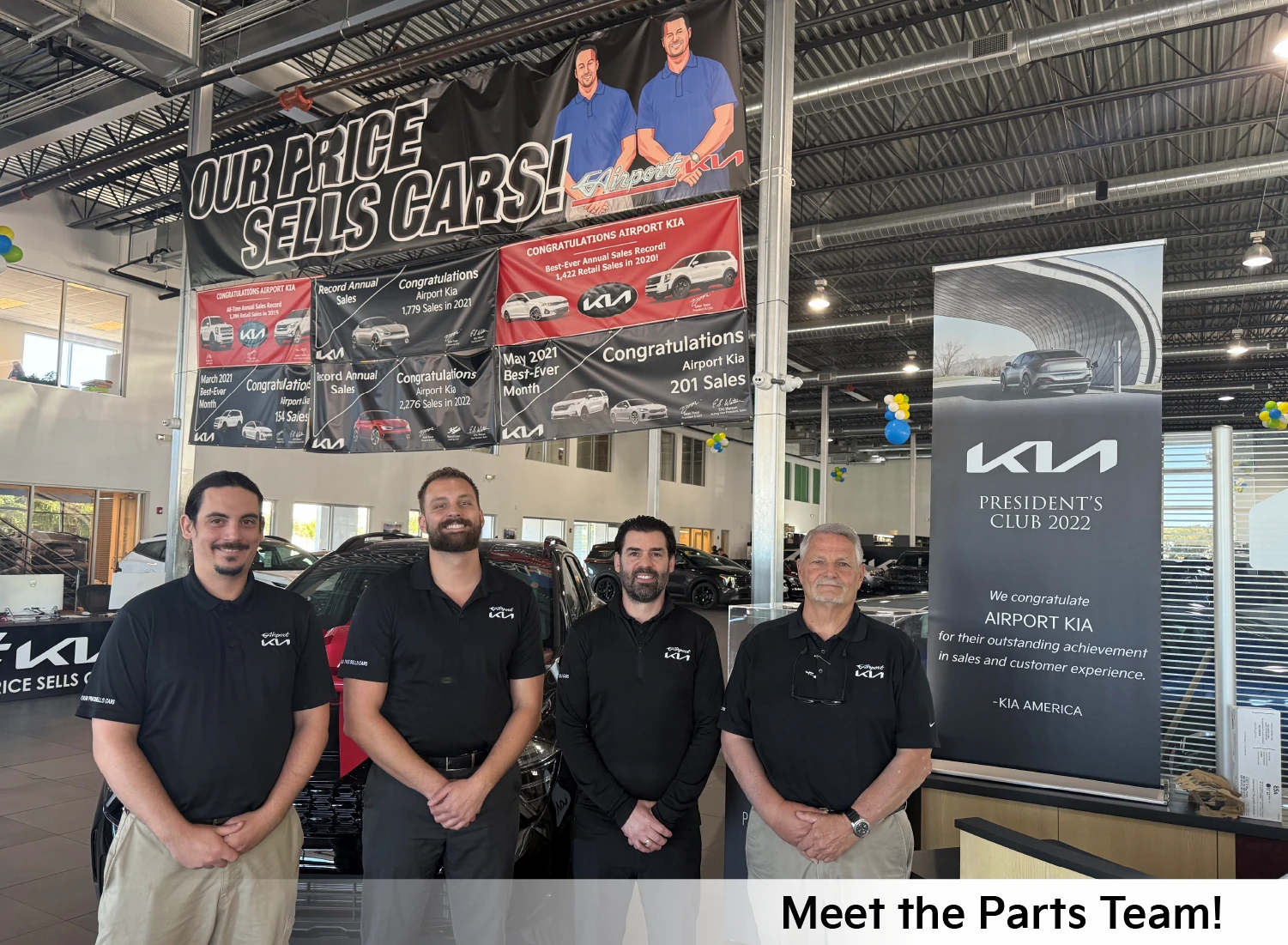 Airport Kia Parts Department team members standing in the showroom beneath sales-achievement banners and a Kia President's Club 2022 award sign, with a "Meet the Parts Team!" caption overlaid on the photo.