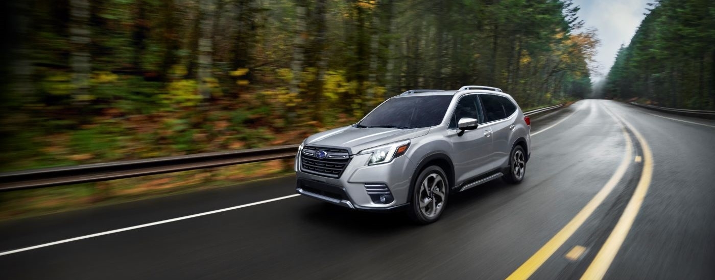 Grey 2023 Subaru Forester driving down a winding road.