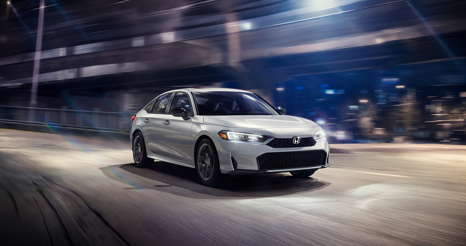 2026 Honda Civic driving at night through a modern urban area, showing compact size, smooth handling, and real-world daily driving capability