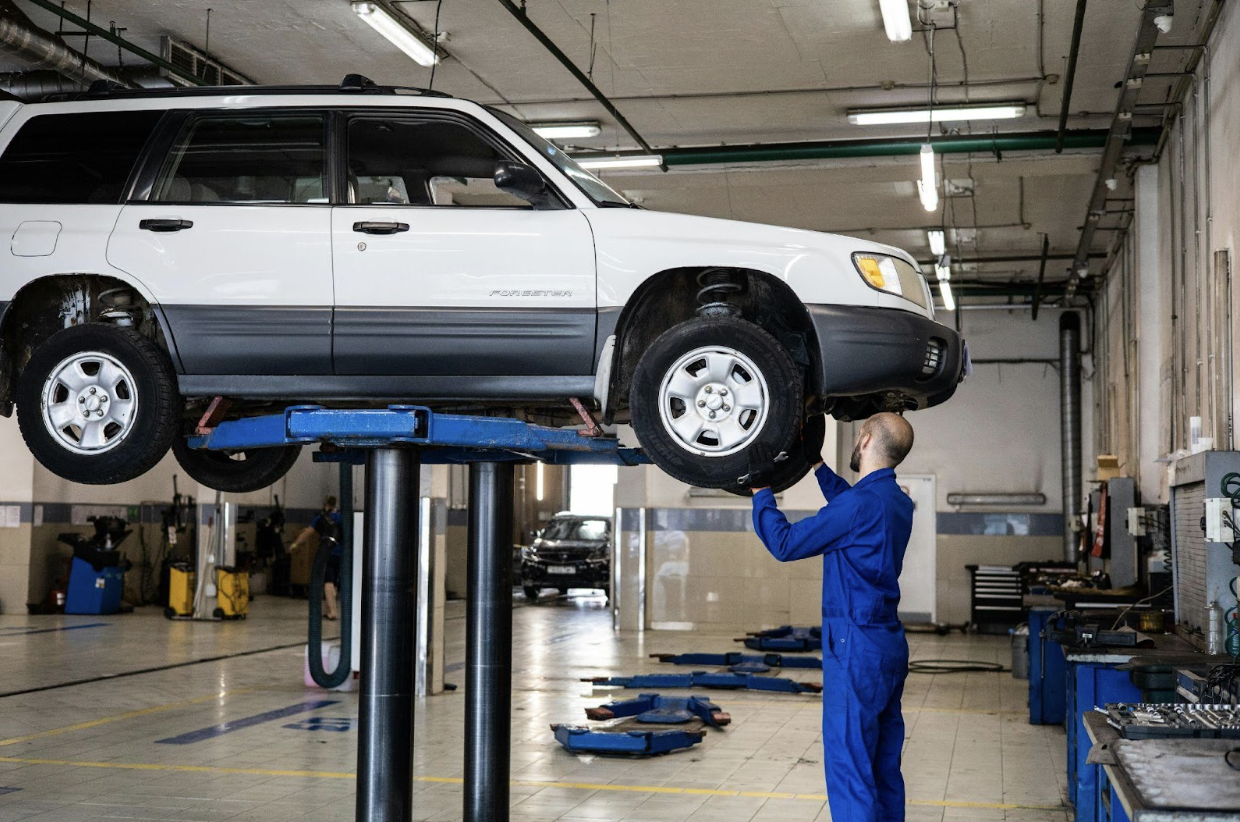 A vehicle on a car lift, being inspected by a professional mechanic