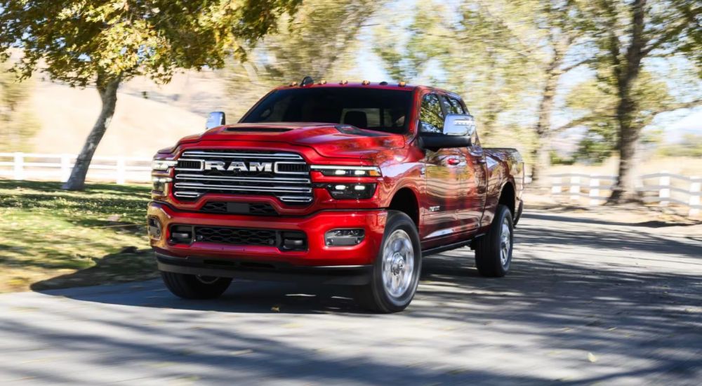 A red 2026 Ram 2500 Laramie driving a country road.