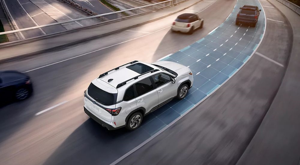 A white 2025 Subaru Forester using the adaptive cruise control feature on the highway.