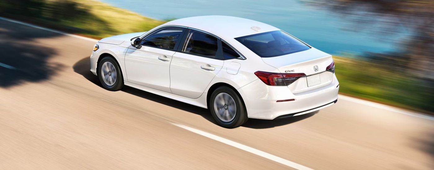 Rear view of a white 2026 Honda Civic driving on a paved road.