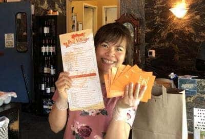 Restaurant owner holding a menu and gift cards