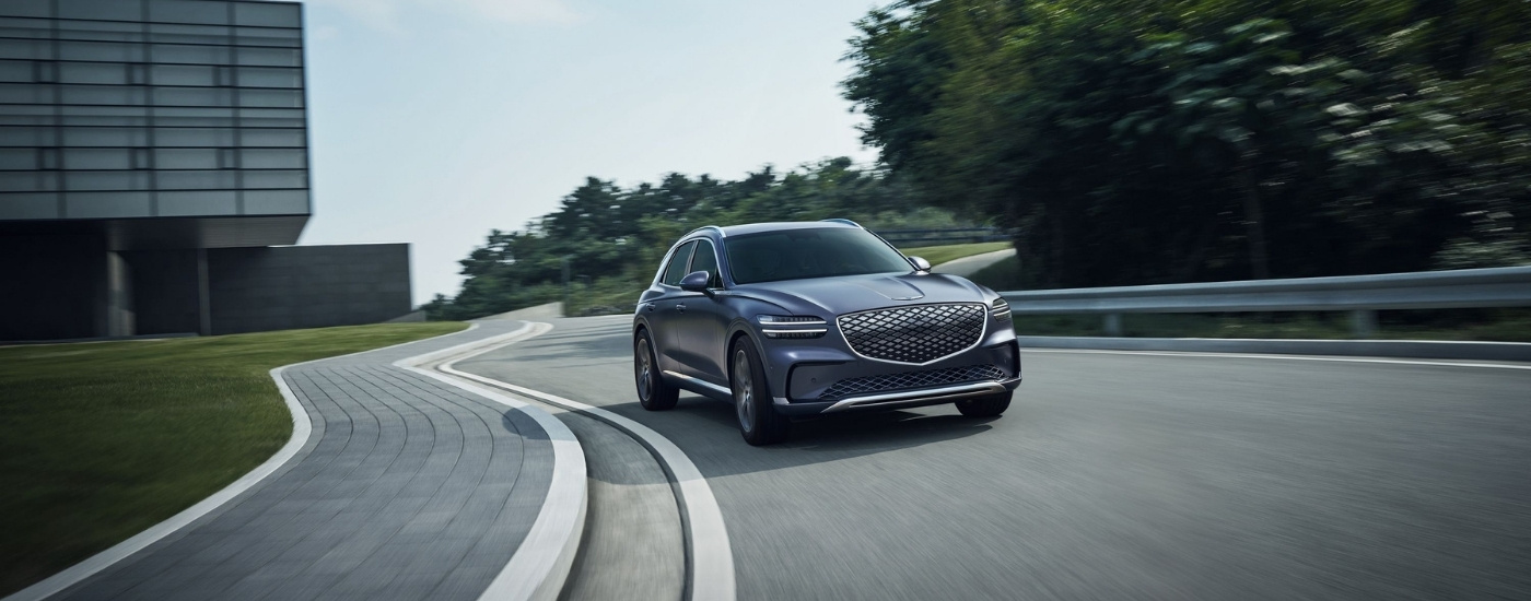 Grey 2026 Genesis GV70 EV driving to look at luxury SUVs for sale near Birmingham