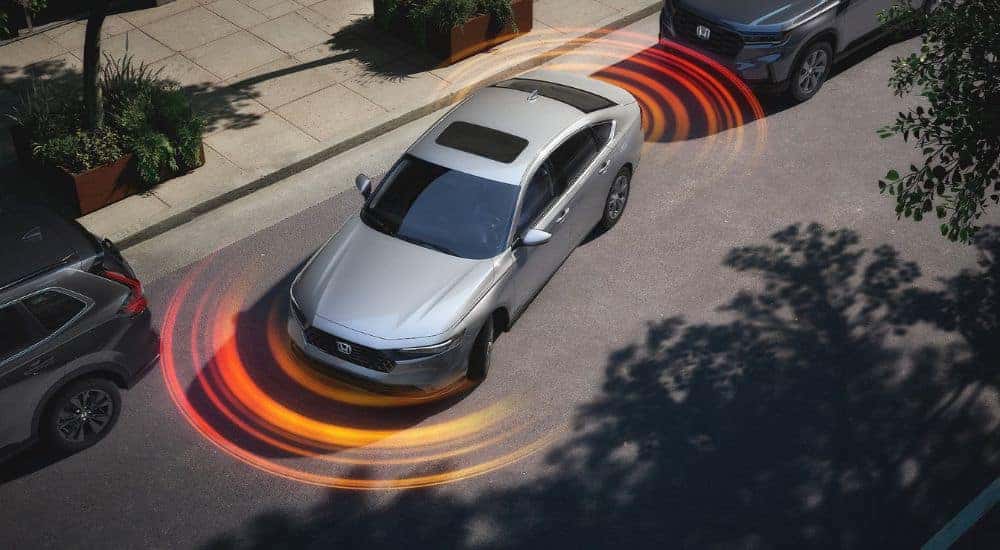 Simulated parking sensor lines emanating from a silver 2025 Honda Accord Hybrid while parallel parking.