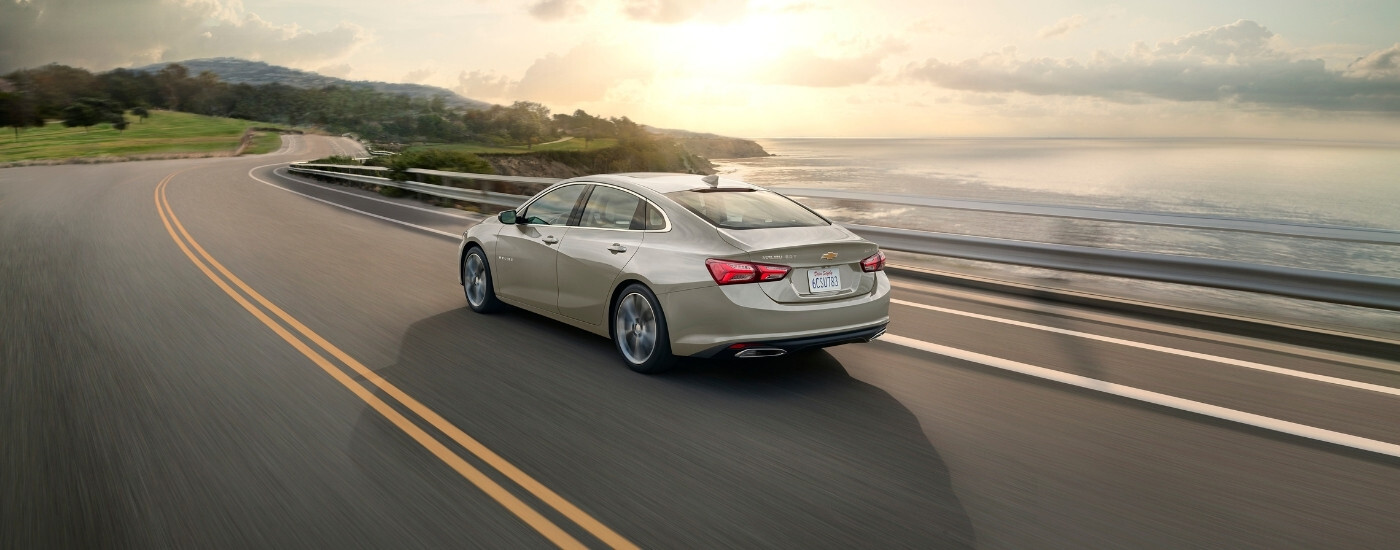 A tan 2024 Chevy Malibu from the rear at an angle.