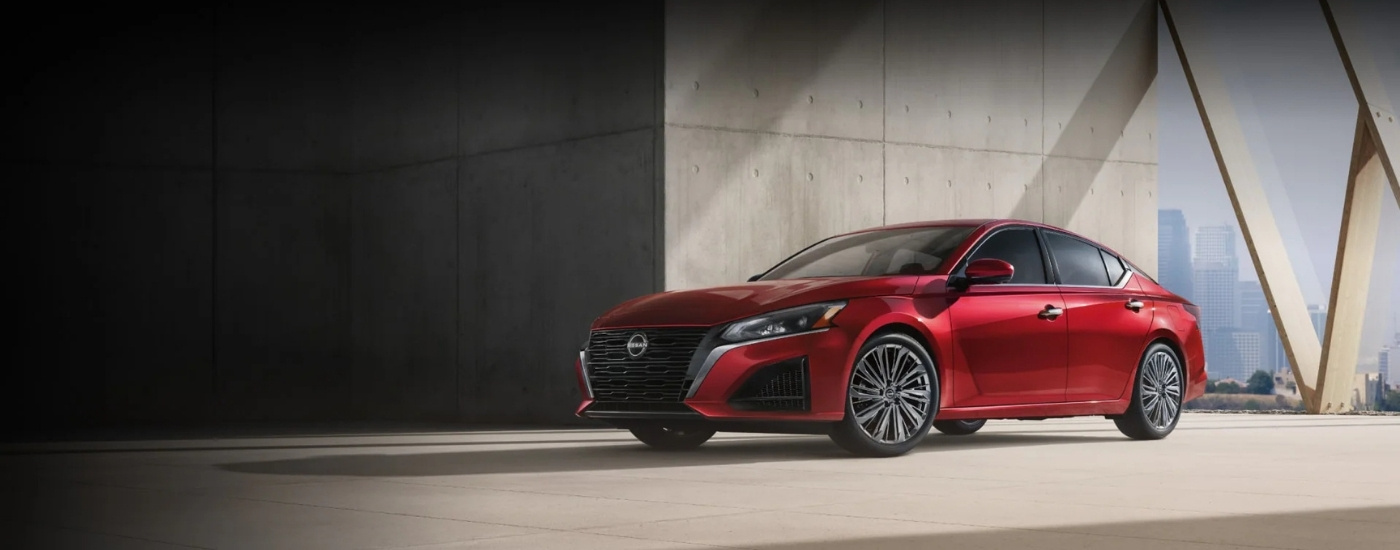 Nissan Altima 2025 rojo estacionado cerca de una pared de concreto