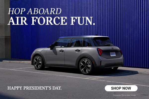 Gray MINI 4 Door parked in front of a blue wall.