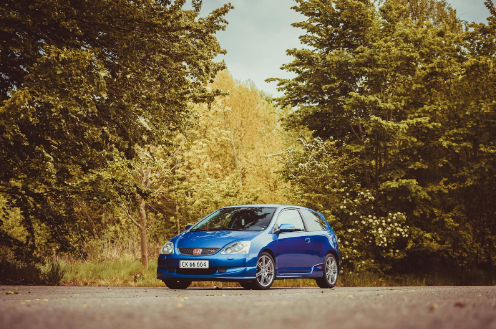 Used Blue Honda Civic parked under trees in a forest park.