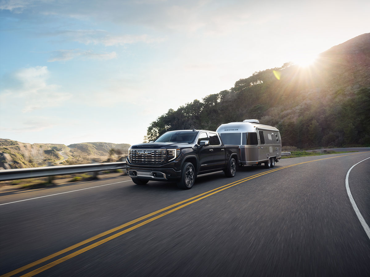 GMC Sierra Towing Airstream Trailer on curved road.