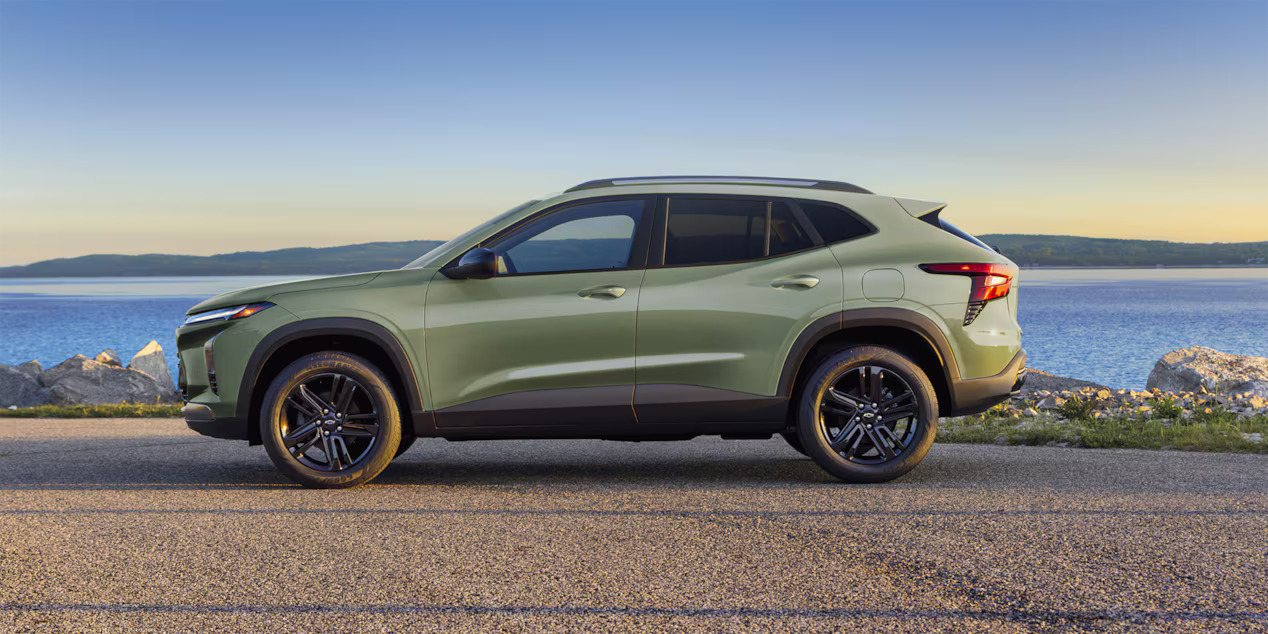 A green car parked by a body of water.