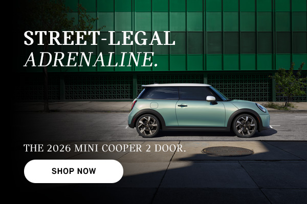 Mint green MINI Cooper 2-door parked on a city street with building backdrop, with ad text promoting the 2026 model and a “Shop Now” button.