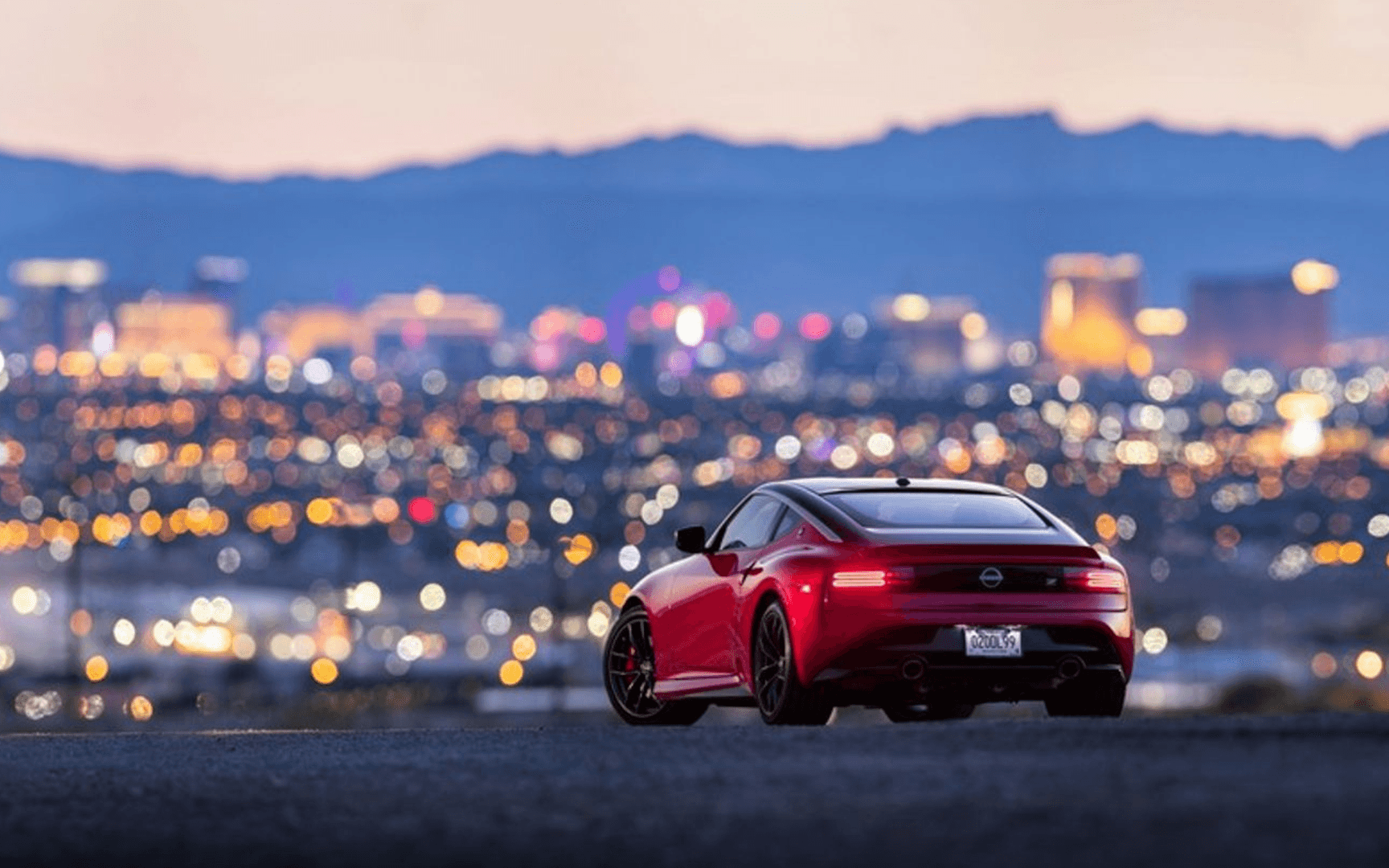 Red Nissan Z parked on an overlook above the Las Vegas skyline at dusk