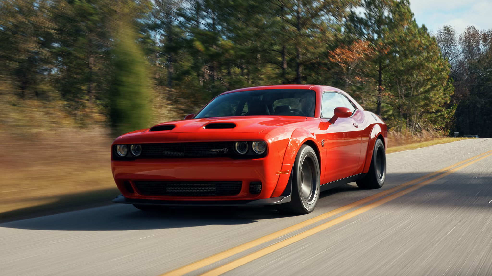 A red 2022 dodge challenger driving down the road.