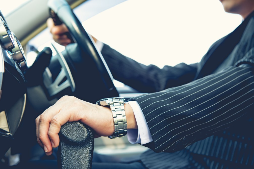 well-dressed man's hand grips steering wheel