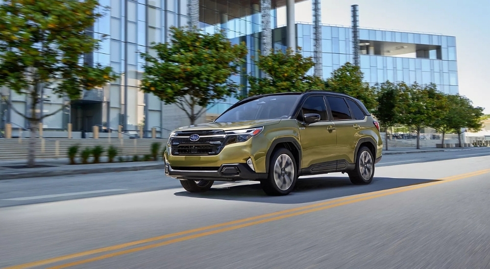 A green Subaru Forester Hybrid for sale driving on a city street.
