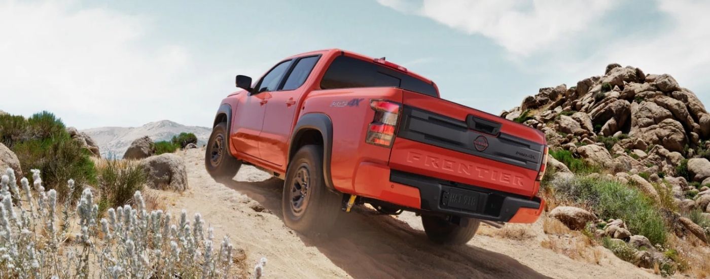 Orange 2025 Nissan Frontier PRO-4X driving on a hill