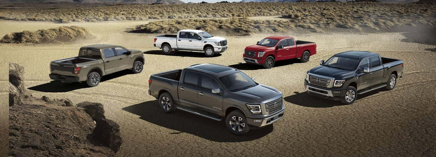 Five 2021 Nissan Titan pickup trucks parked on a desert dirt road