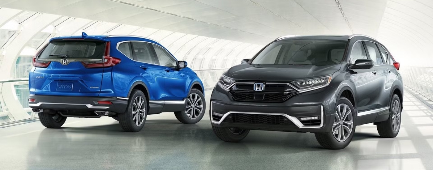 A blue and a grey 2021 Honda CR-V Touring are parked in a bright showroom at a Rochester Honda CR-V dealer.