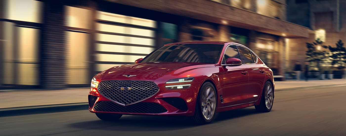 Red 2020 Genesis G70 driving down a city street.