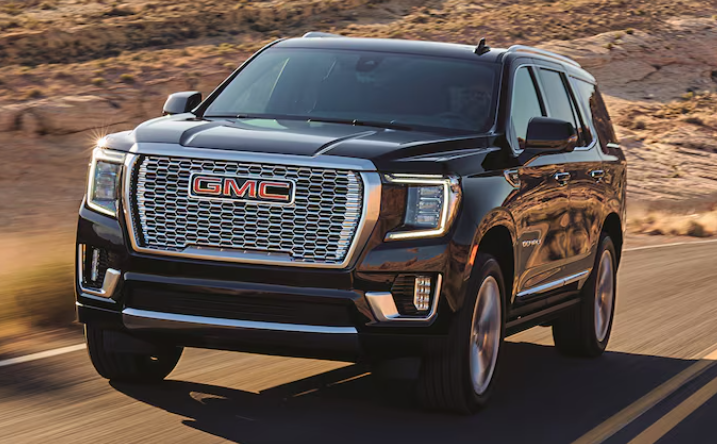 New GMC Yukon driving down a desert road.