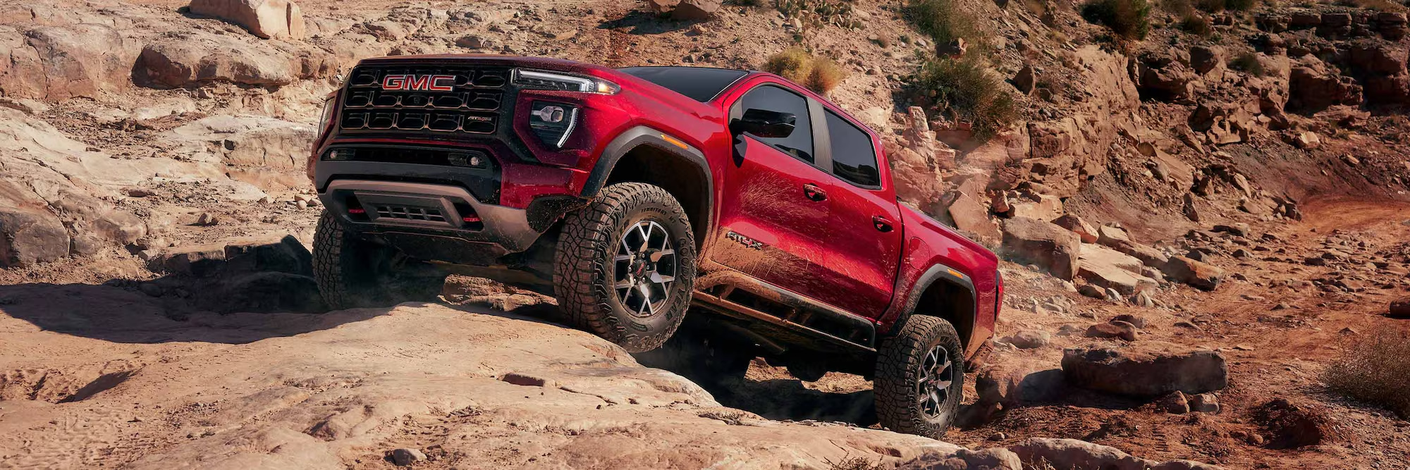 Red GMC Canyon AT4X climbing a rocky off-road trail