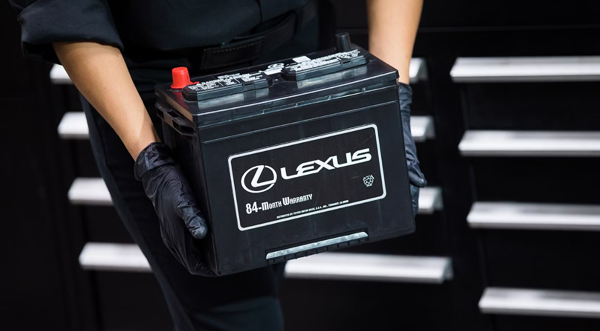A Lexus service tech's hands carry a Lexus genuine battery.