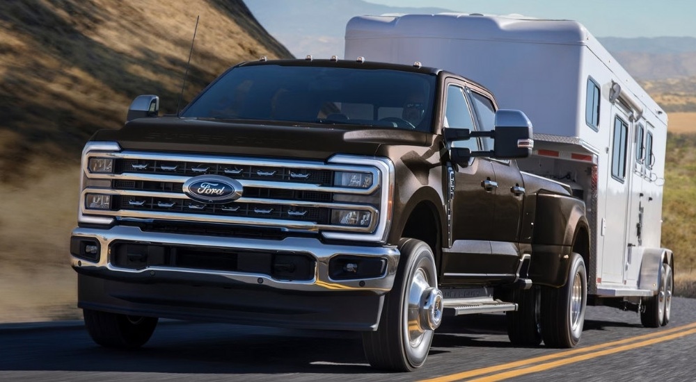 A grey 2023 Ford F-350 Super Duty Dually is shown from the front while towing a trailer.