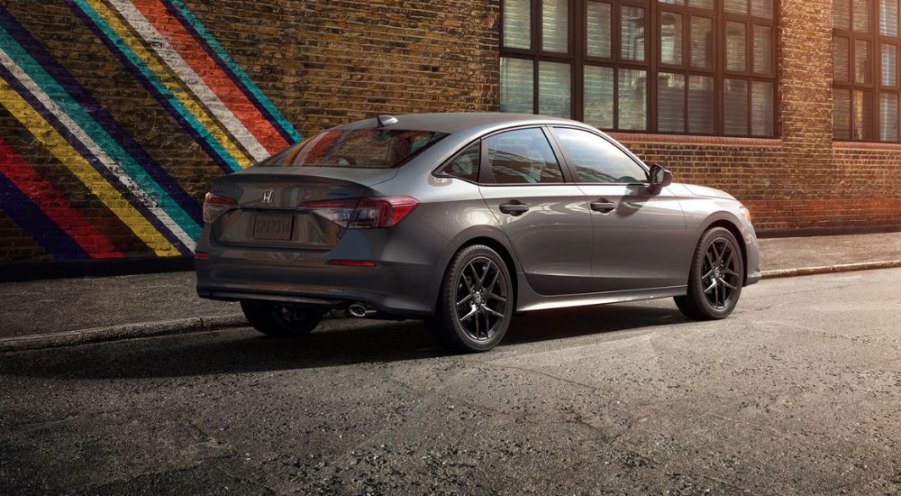 A gray 2026 Honda Civic Sport parked by a painted brick wall.