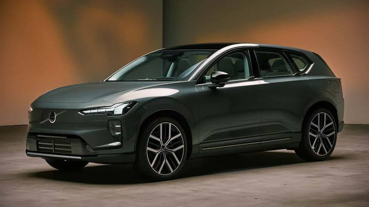 2027 Volvo EX60 electric SUV in dark green parked in a studio with warm orange lighting