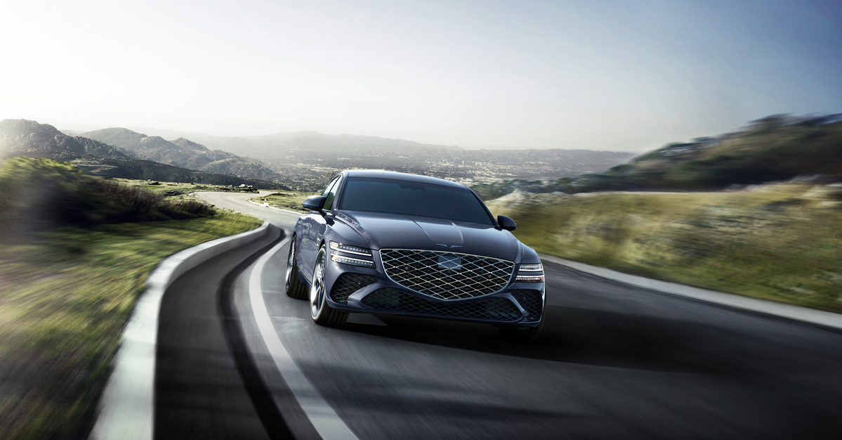 7/8 front passenger view of Genesis G80 in Ceres Blue driving country road with rolling hills