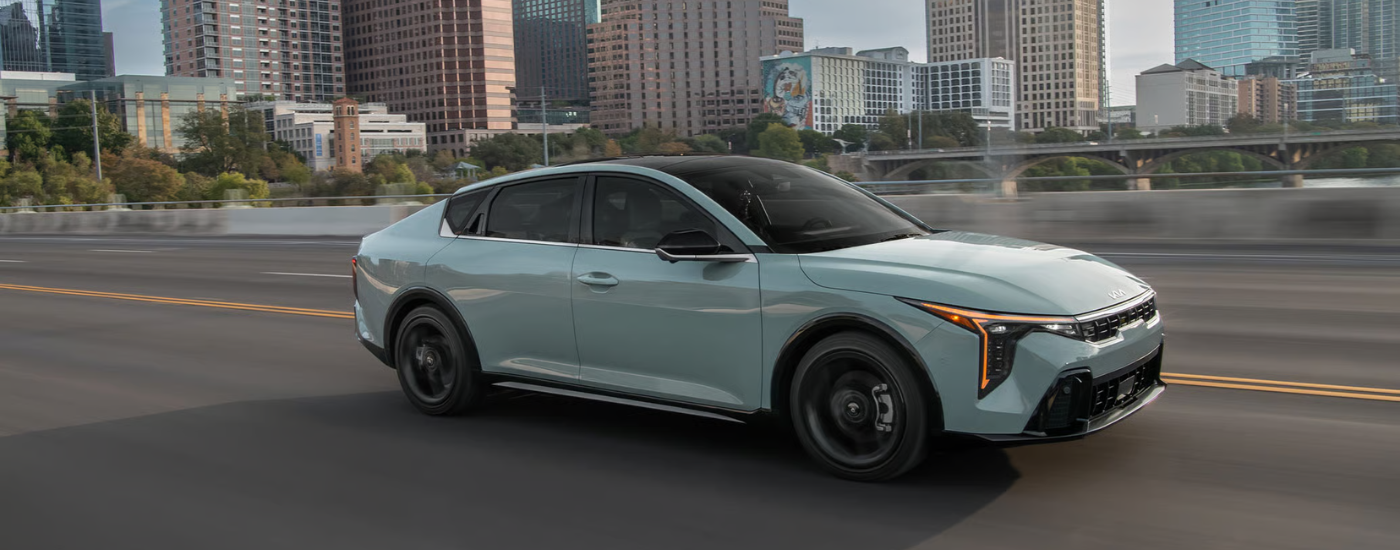 Blue 2026 Kia K4 driving through a city