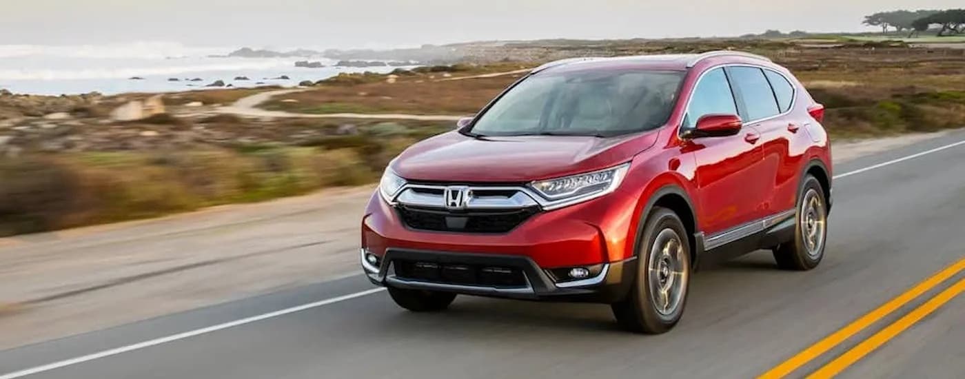 Red 2018 Honda CR-V driving down an open road.