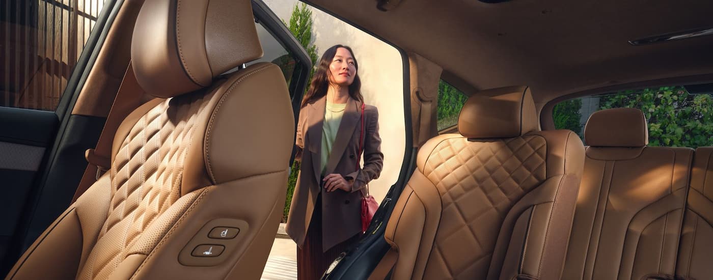 Woman opening the back door of a 2025 Genesis GV80 for sale near The Villages