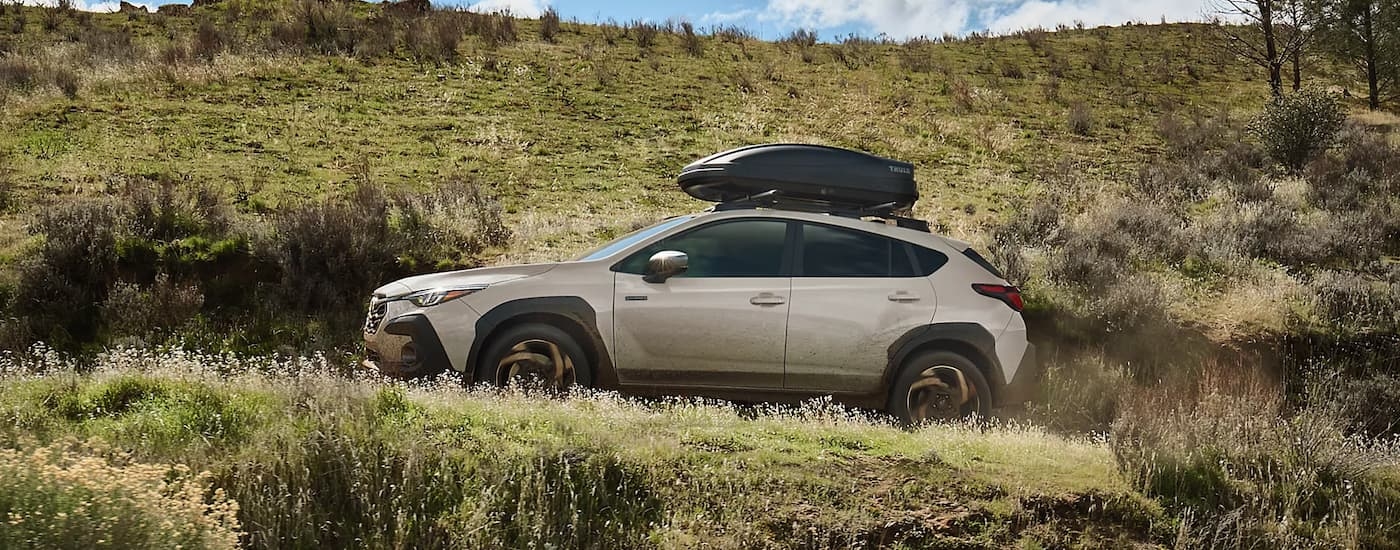 Side of a white 2026 Subaru Crosstrek Hybrid driving off-road.