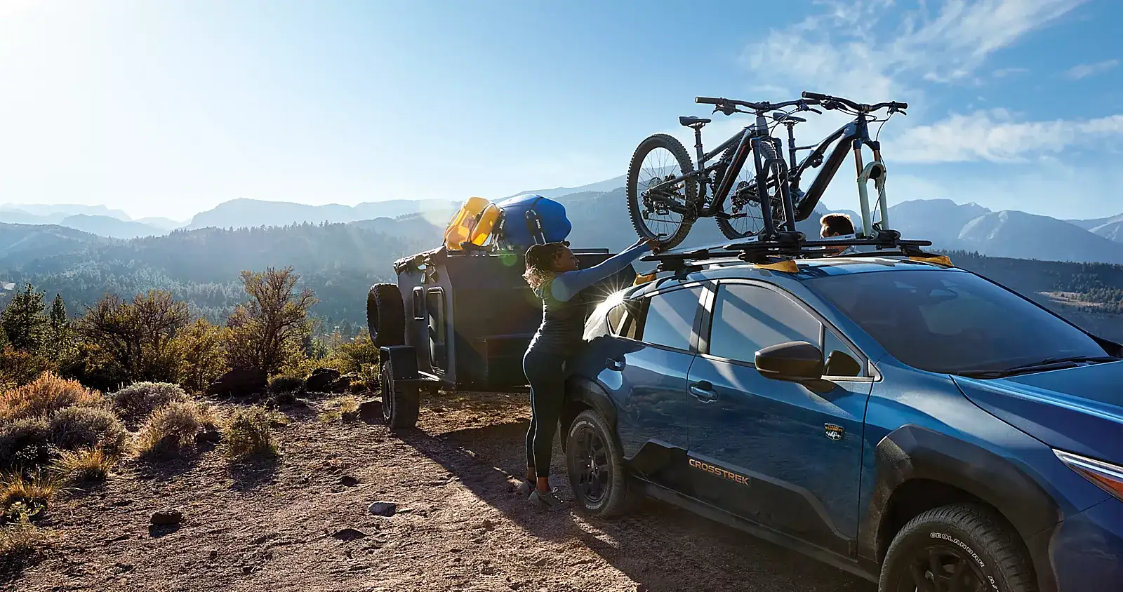 Subaru with bikes on a roof rack parked at a mountain campsite