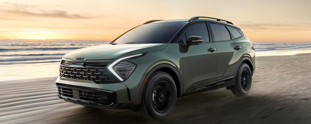 2025 Kia Sportage driving on a beach at sunset, showcasing its sleek design and modern features, relevant to Kiefer Kia's guide on Sportage trims and pricing.