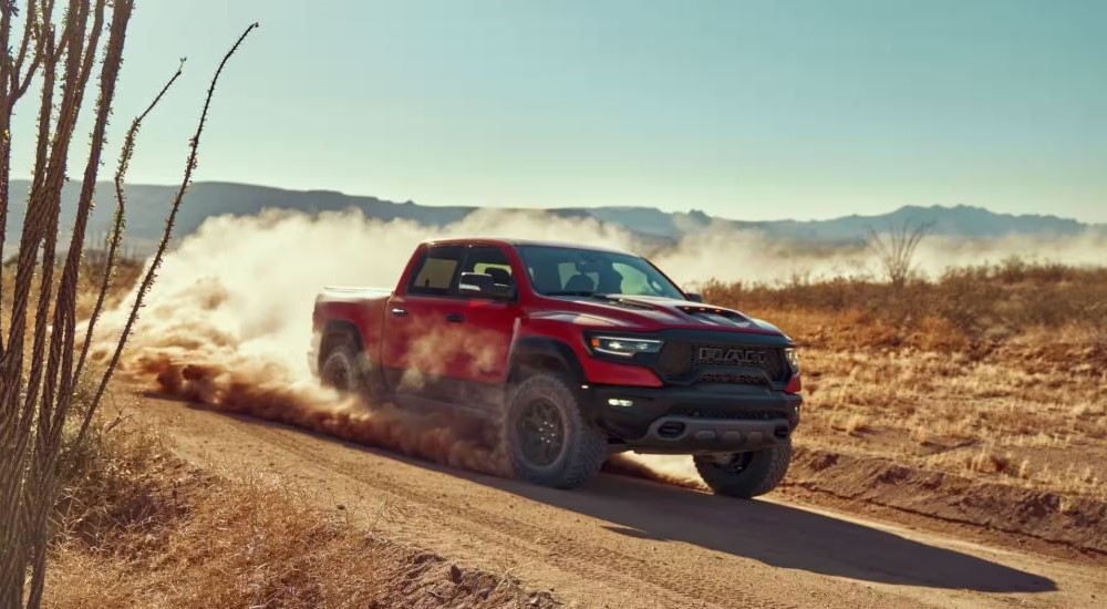 A red 2022 Ram 1500 TRX is shown kicking up dust on a trail.