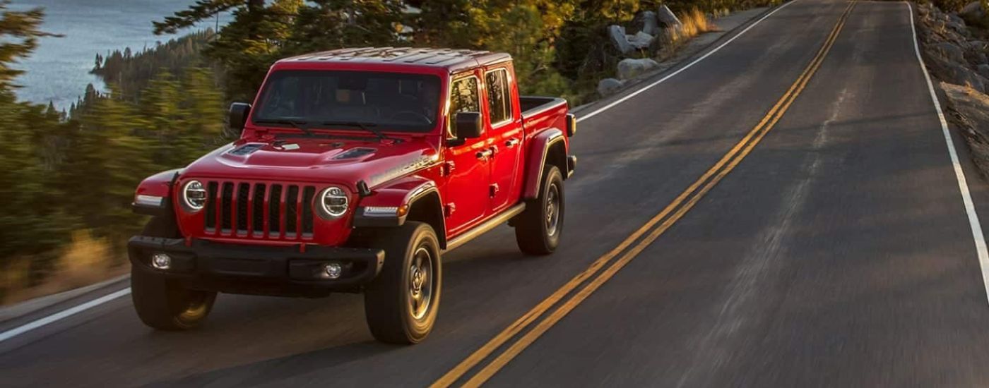 A red 2021 Jeep Gladiator Rubicon is shown driving on an open road after leaving a Jeep dealer near Sycamore.