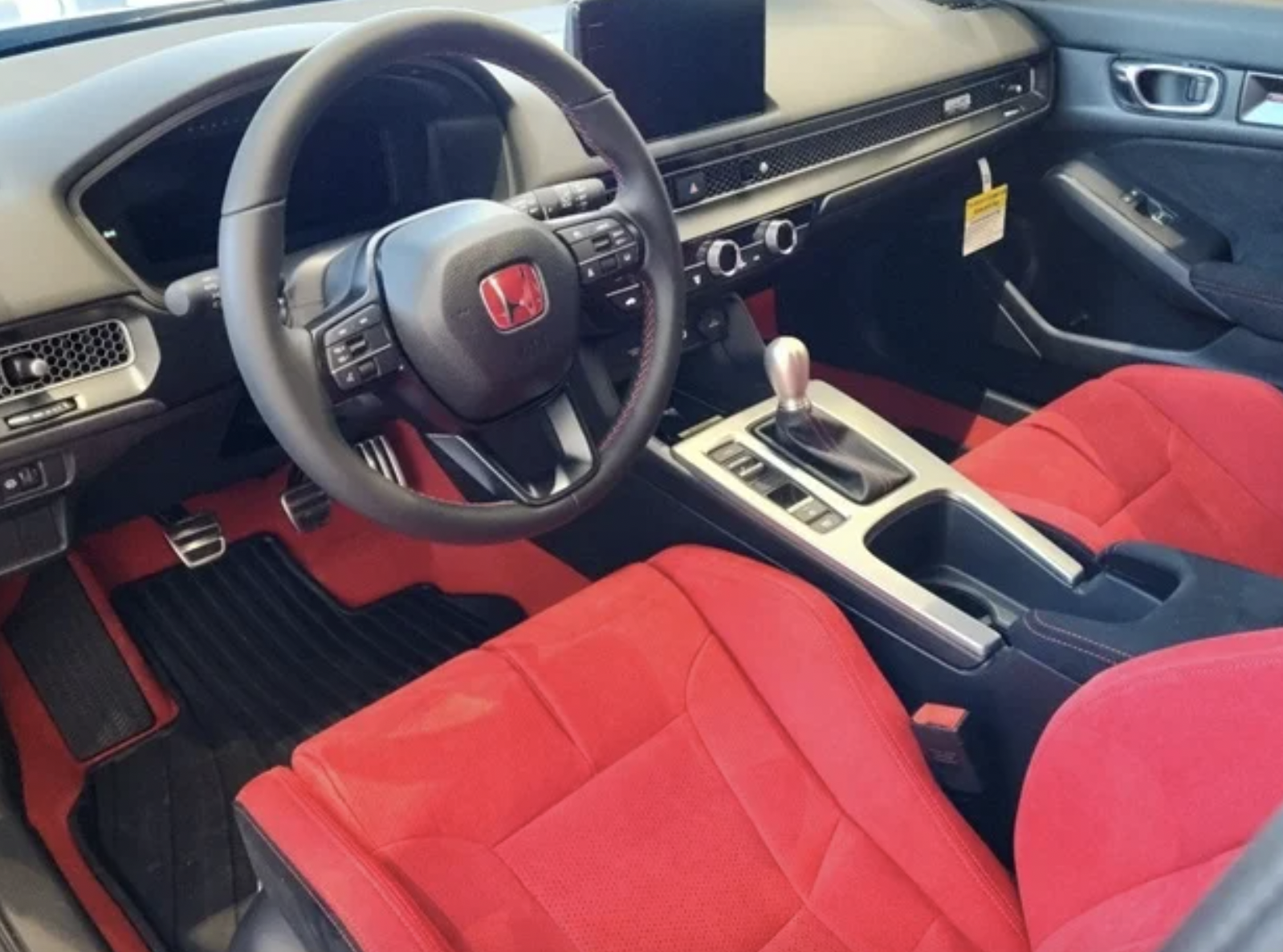 The sporty interior of the 2025 Honda Civic Type R with signature red and black color scheme, low bucket seats, and aluminum accents.