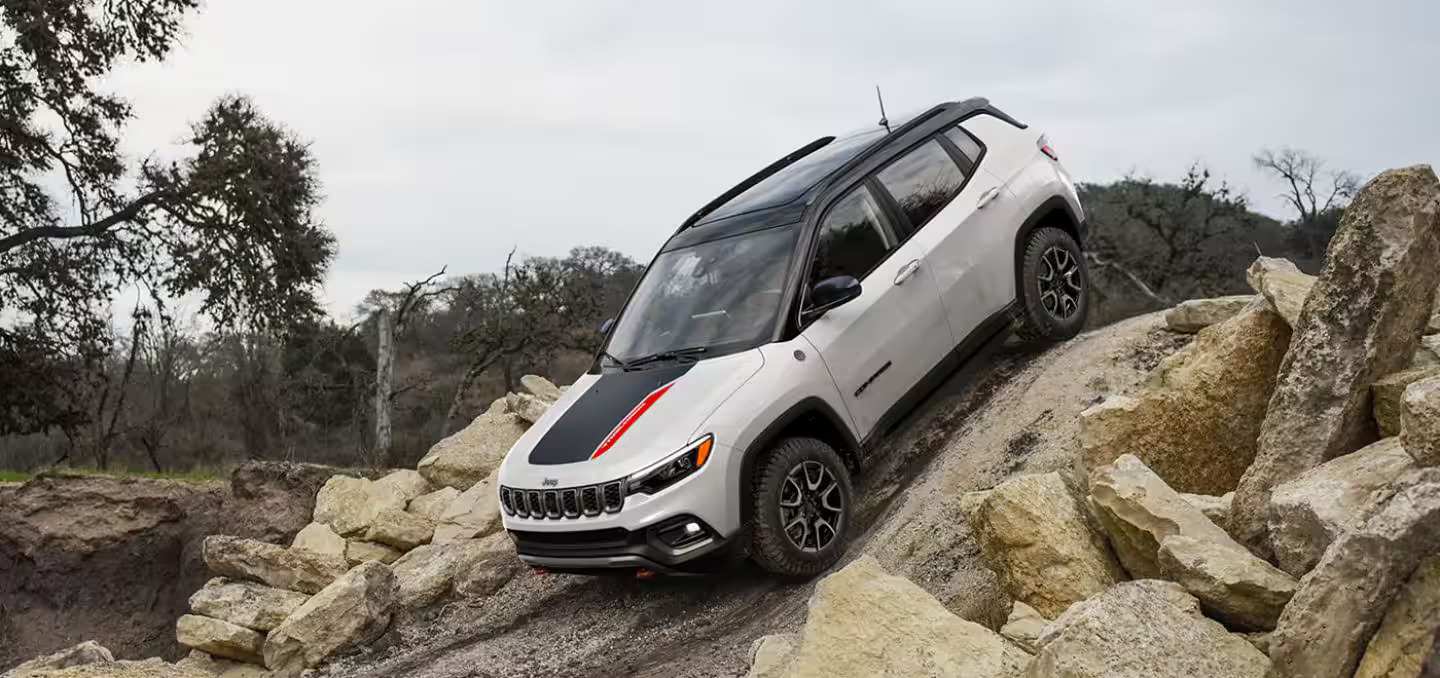 A white jeep driving down a hill.