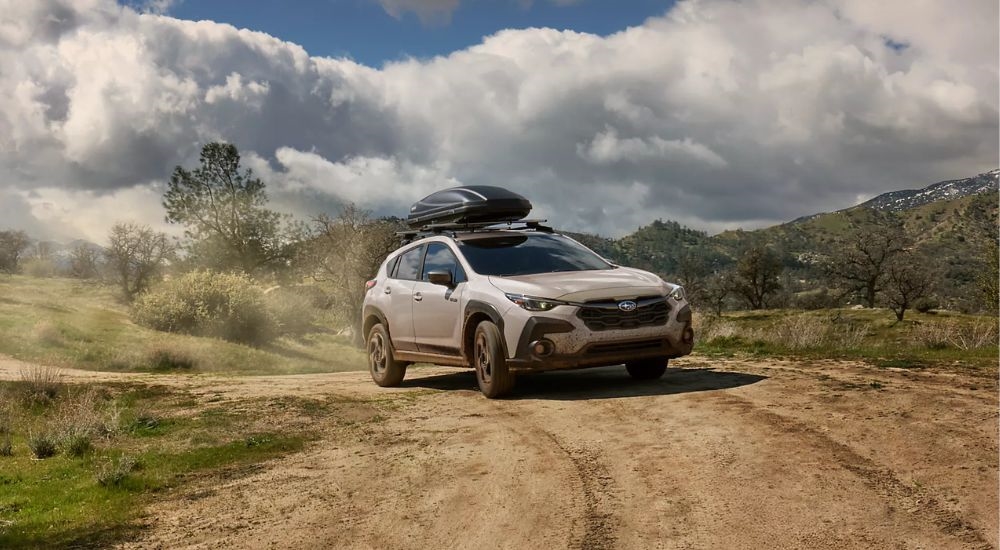 A white 2026 Subaru Crosstrek Limited Hybrid driving on a dirt road.