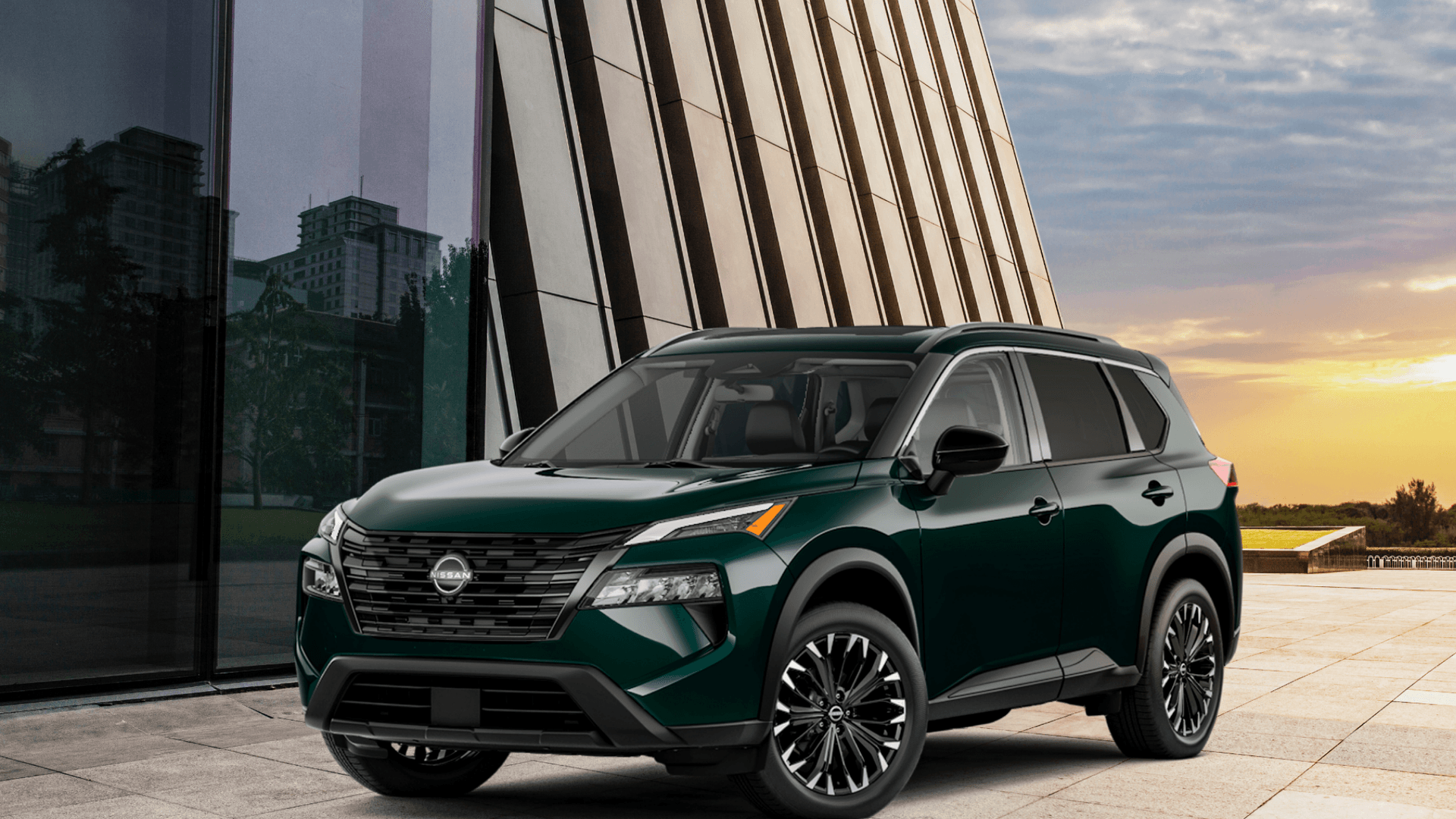 2026 Nissan Rogue® dark green SUV parked beside a modern building at sunset in front three-quarter view.
