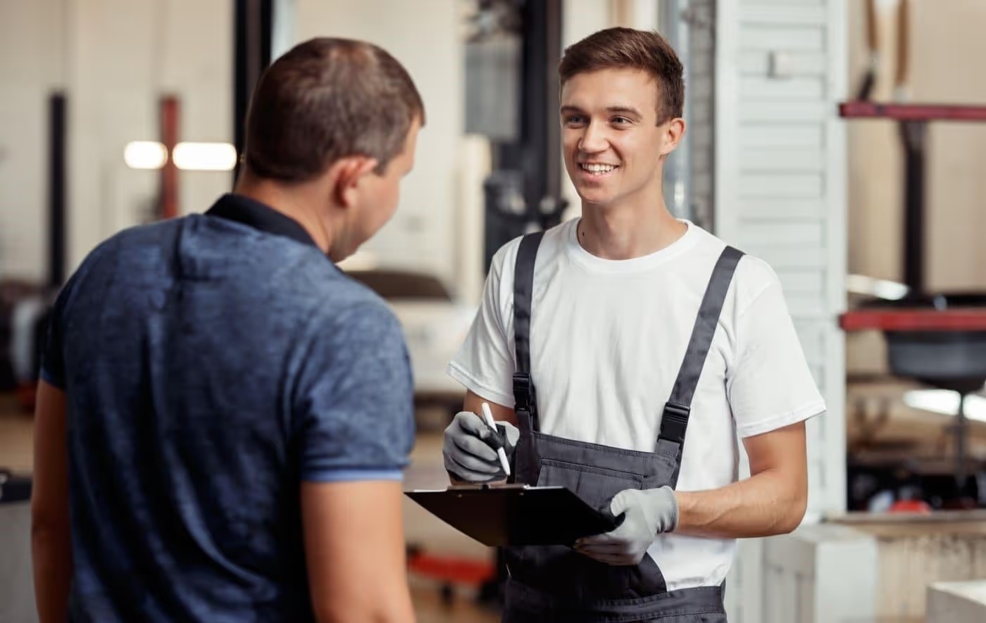 Service technician with a clipboard talking with a customer in the service center