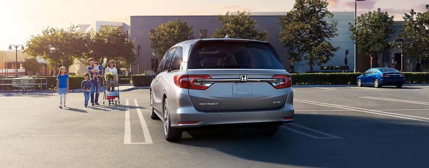 A silver 2023 Honda Odyssey is shown from the rear parked in a store lot.