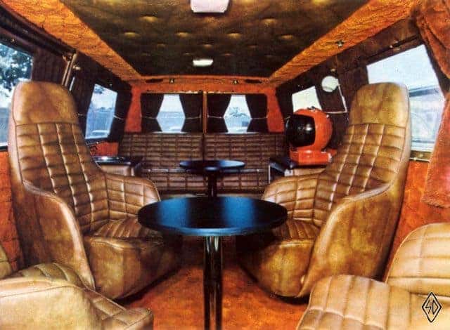 Custom minivan interior with tan leather captain's chairs and a table