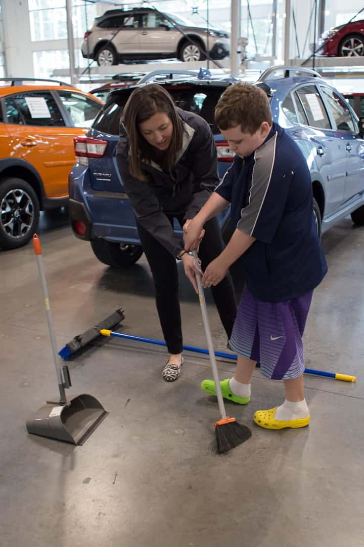 Victory Academy intern sweeping the showroom floor with a staff member