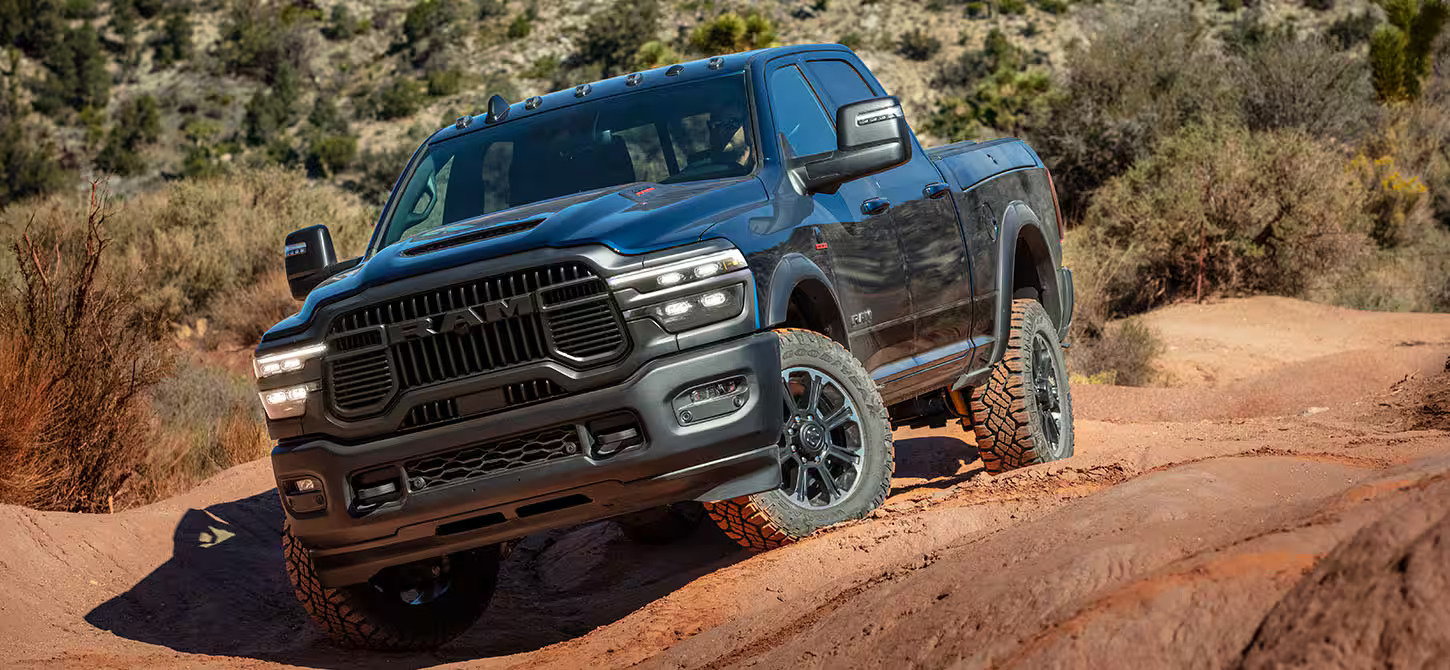 A black ram truck driving on dirt.